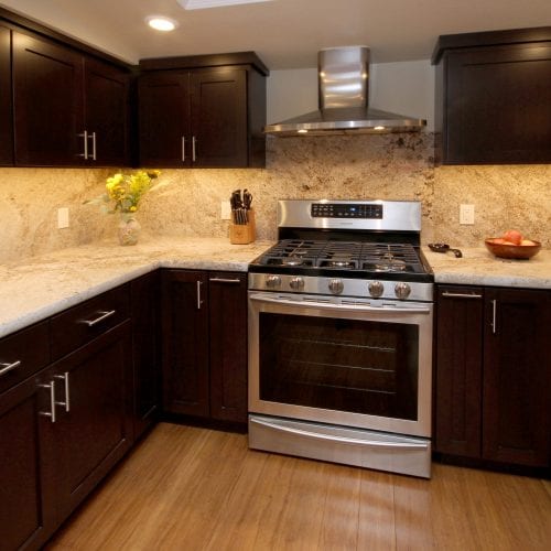 Stainless steel oven between two rows of dark wood cabinets