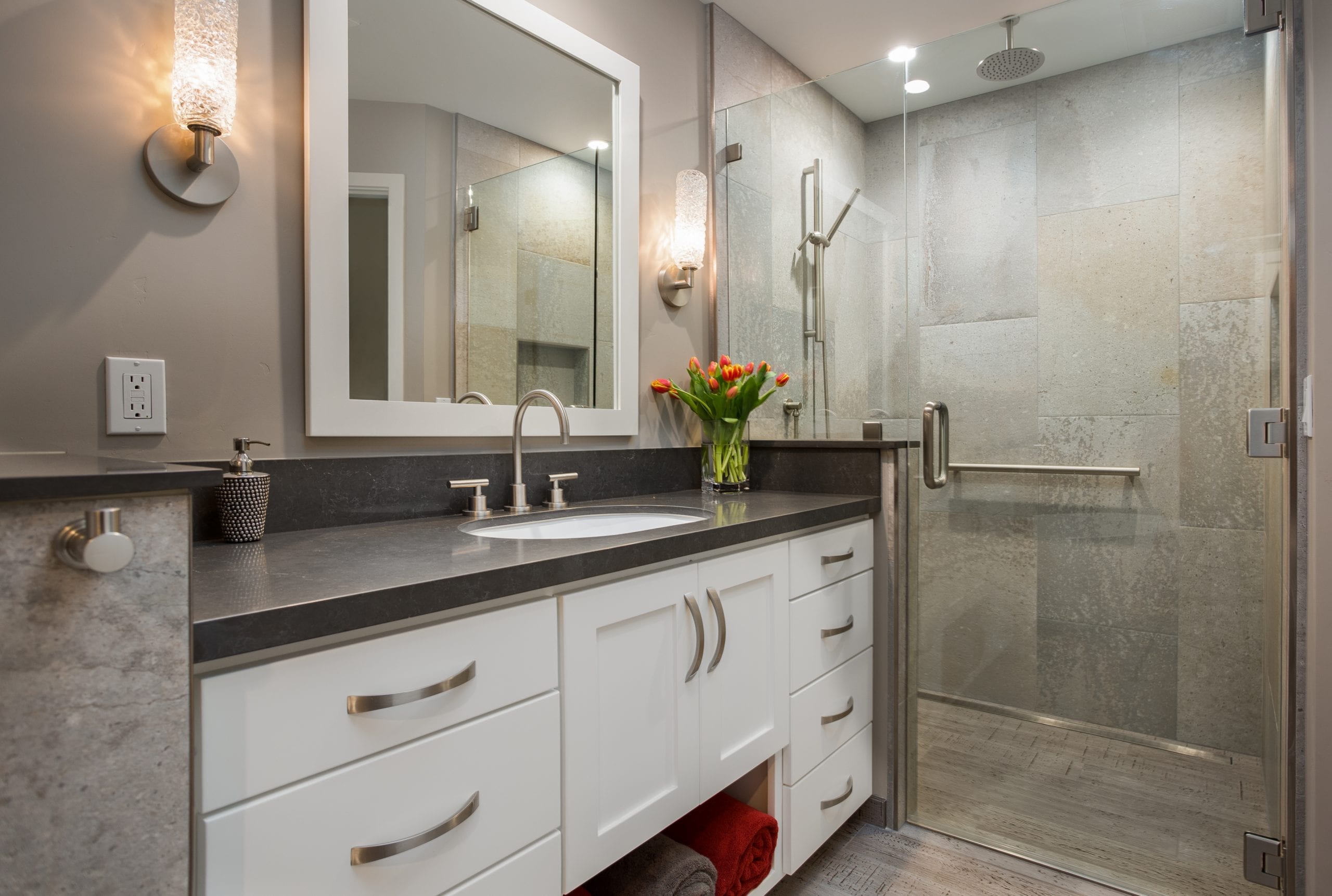 Counter with black counter next to glass shower