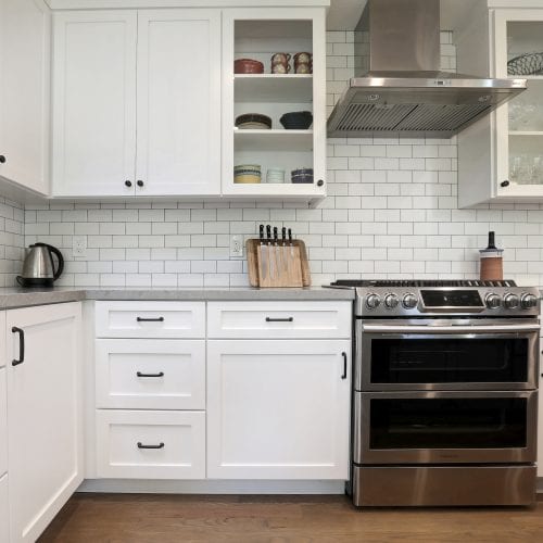 White cabinets and cupboards border metal stove and oven