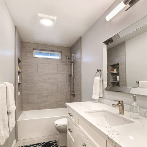 Bathroom with white marble counter and steel framed mirror