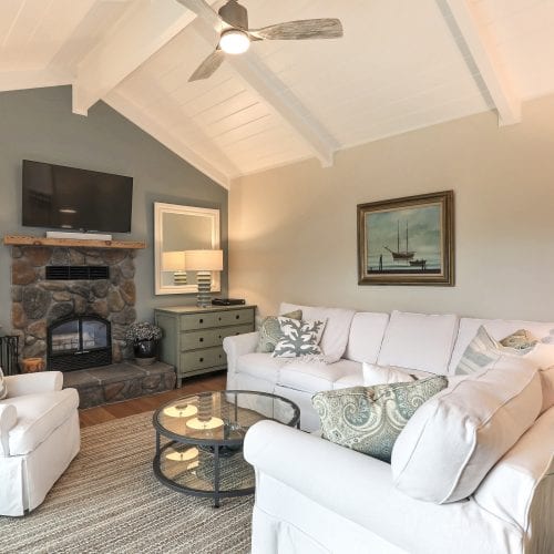 White couches and chair with stone fireplace