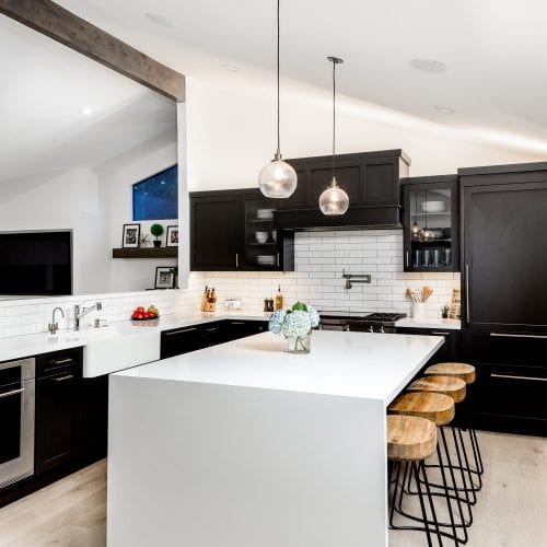 Kitchen with white stand-alone island, open wall frame, and black cabinetry