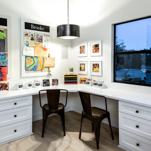 Home office with a white, L-shaped desk and 2 black office chairs