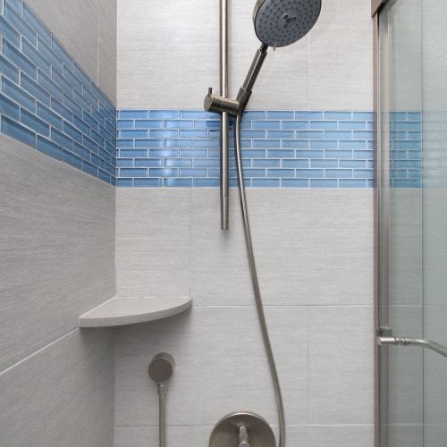 Shower with light blue tile accents and glass sliding door