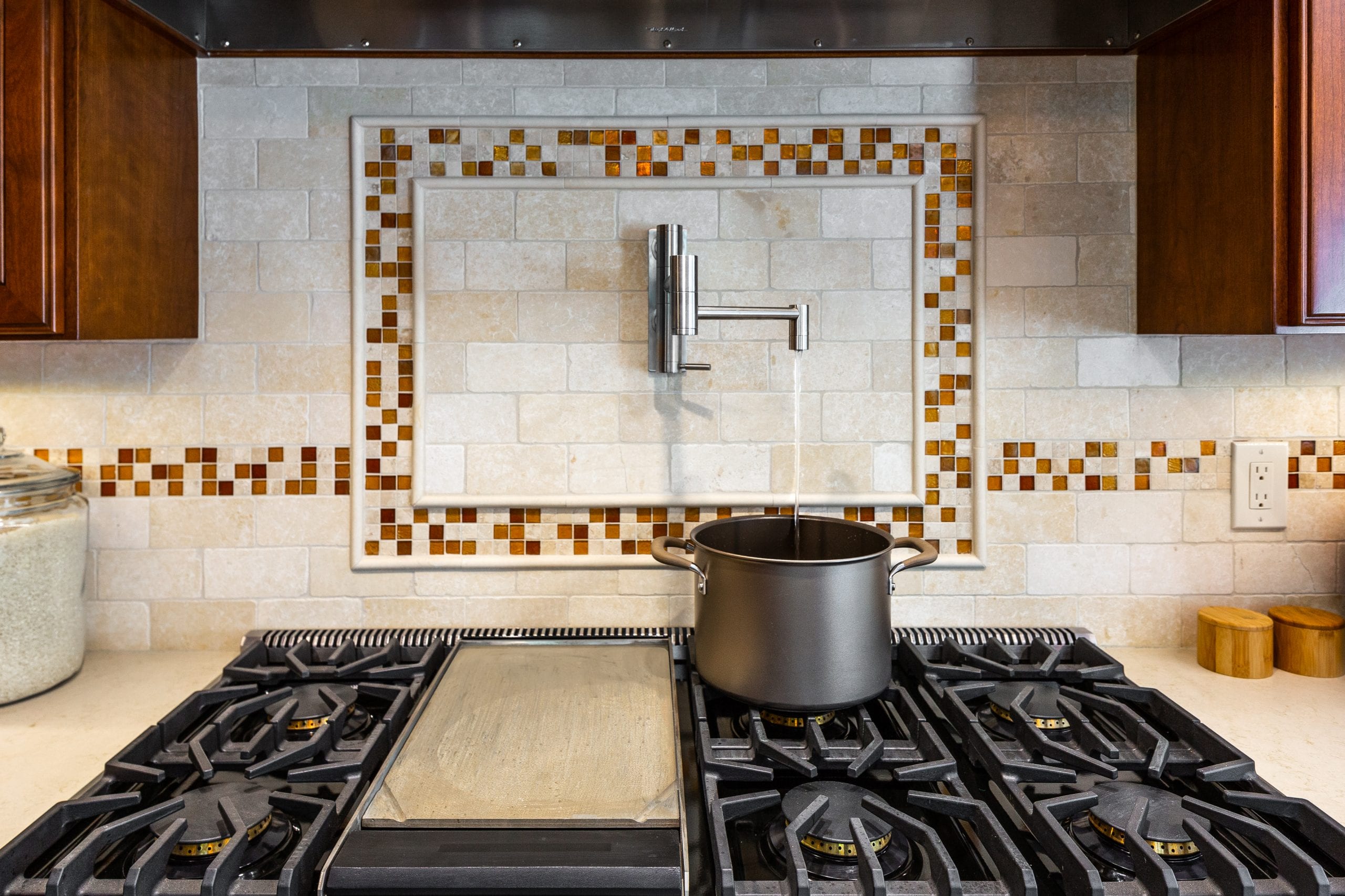 White and orange glass tile backsplash above stovetop