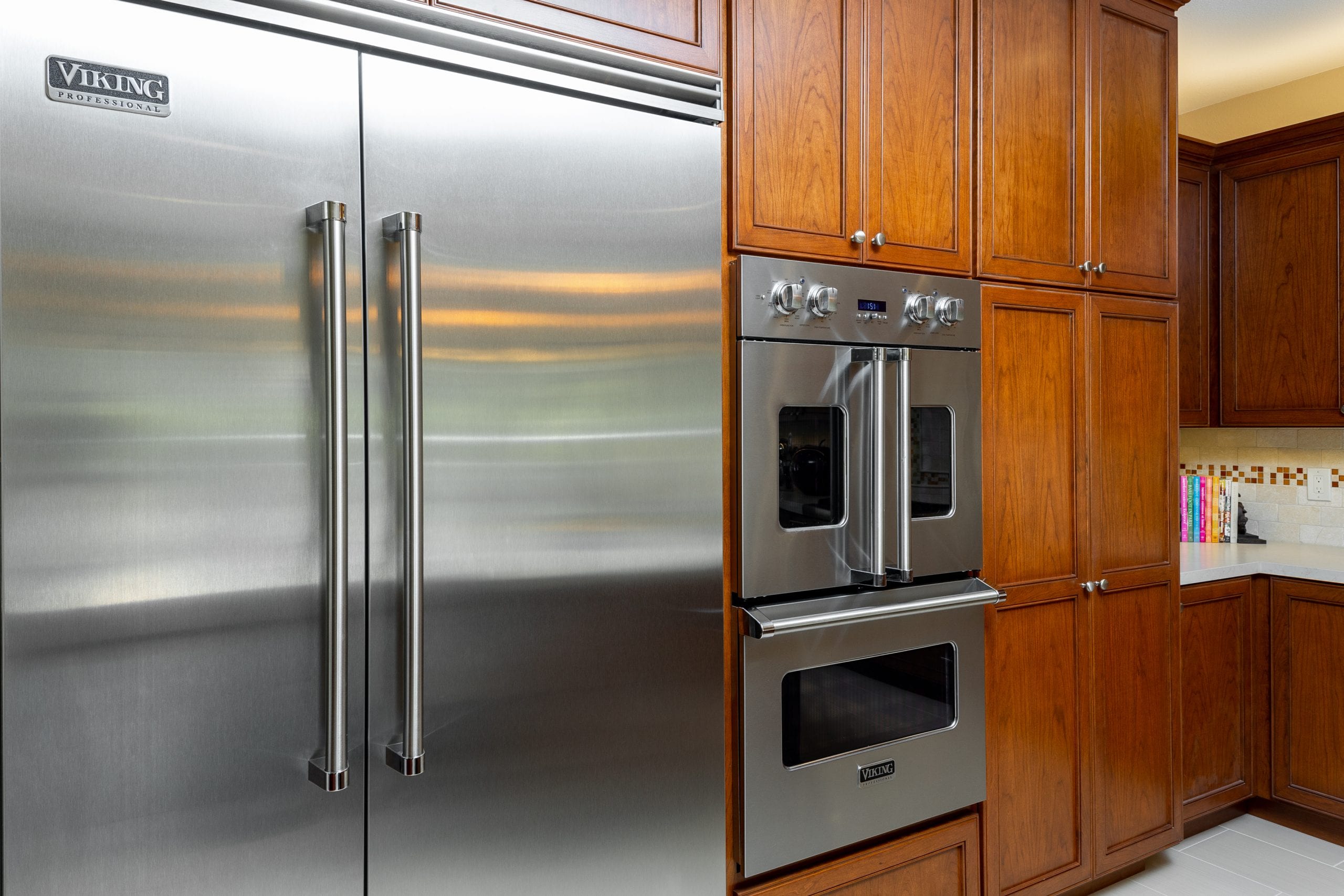 Stainless steel refrigerator next oven embedded into cabinet wall