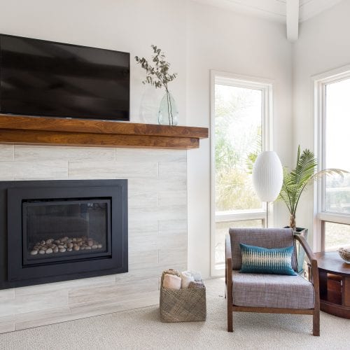 Grey stone fireplace with mounted TV above wooden mantle