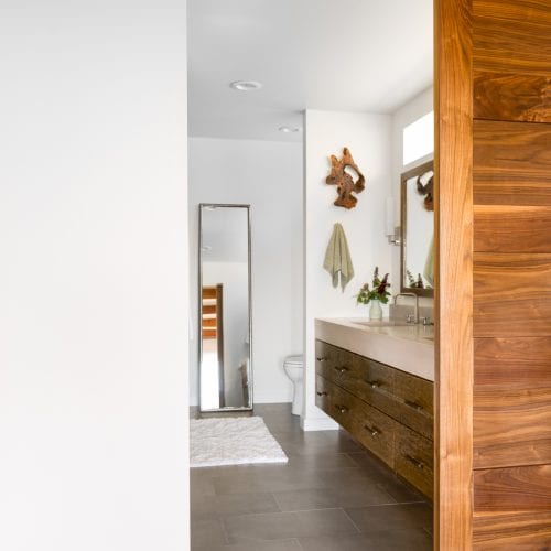 Bathroom entryway with wooden sliding door and vertical mirror