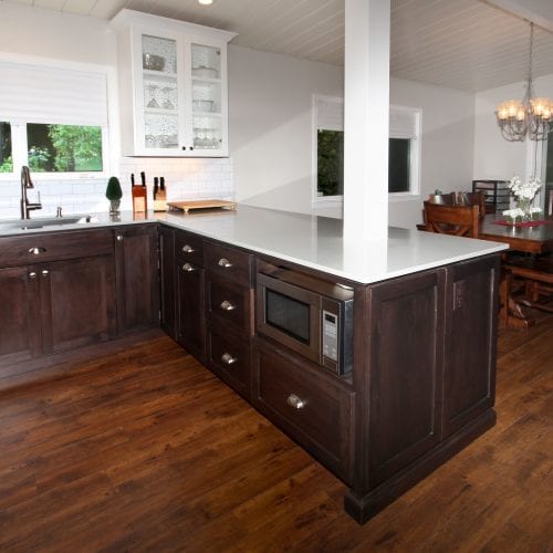 Kitchen with hardwood flooring and white countertops. White support beam mounted in counter