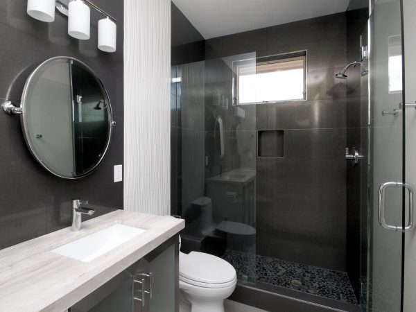 Bathroom with dark color scheme, round mirror and sliding glass door