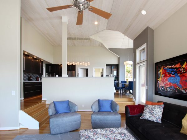 Living room with two blue chairs, a black sofa and wooden ceiling fan