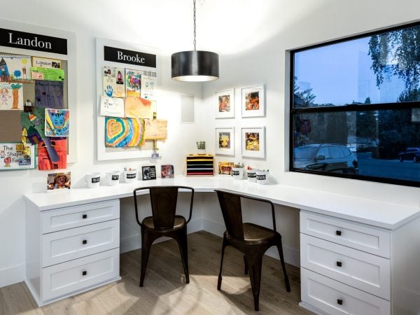 Home office with a white L-shaped desk and two black chairs