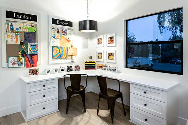 Home office with a white, L-shaped desk and 2 black chairs