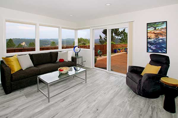 Living room with black furniture, grey wood floor and lots of windows