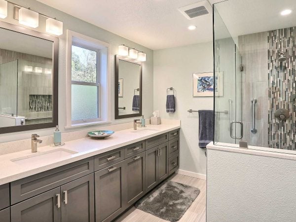 Double vanity bathroom counter with grey cabinets and walk-in shower