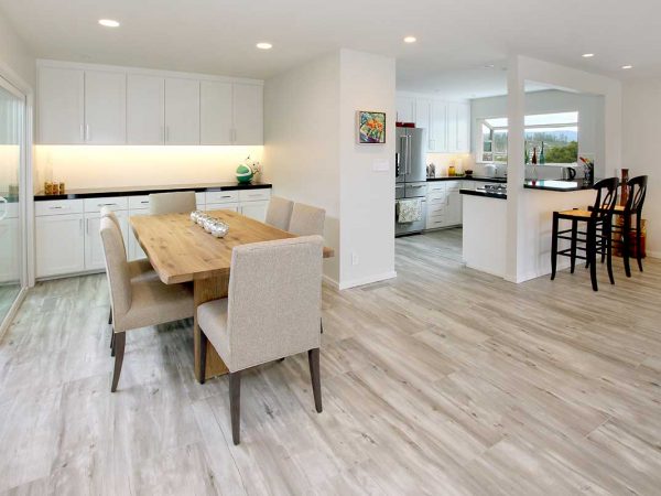 Open dining room and kitchen with white cabinets and wooden flooring