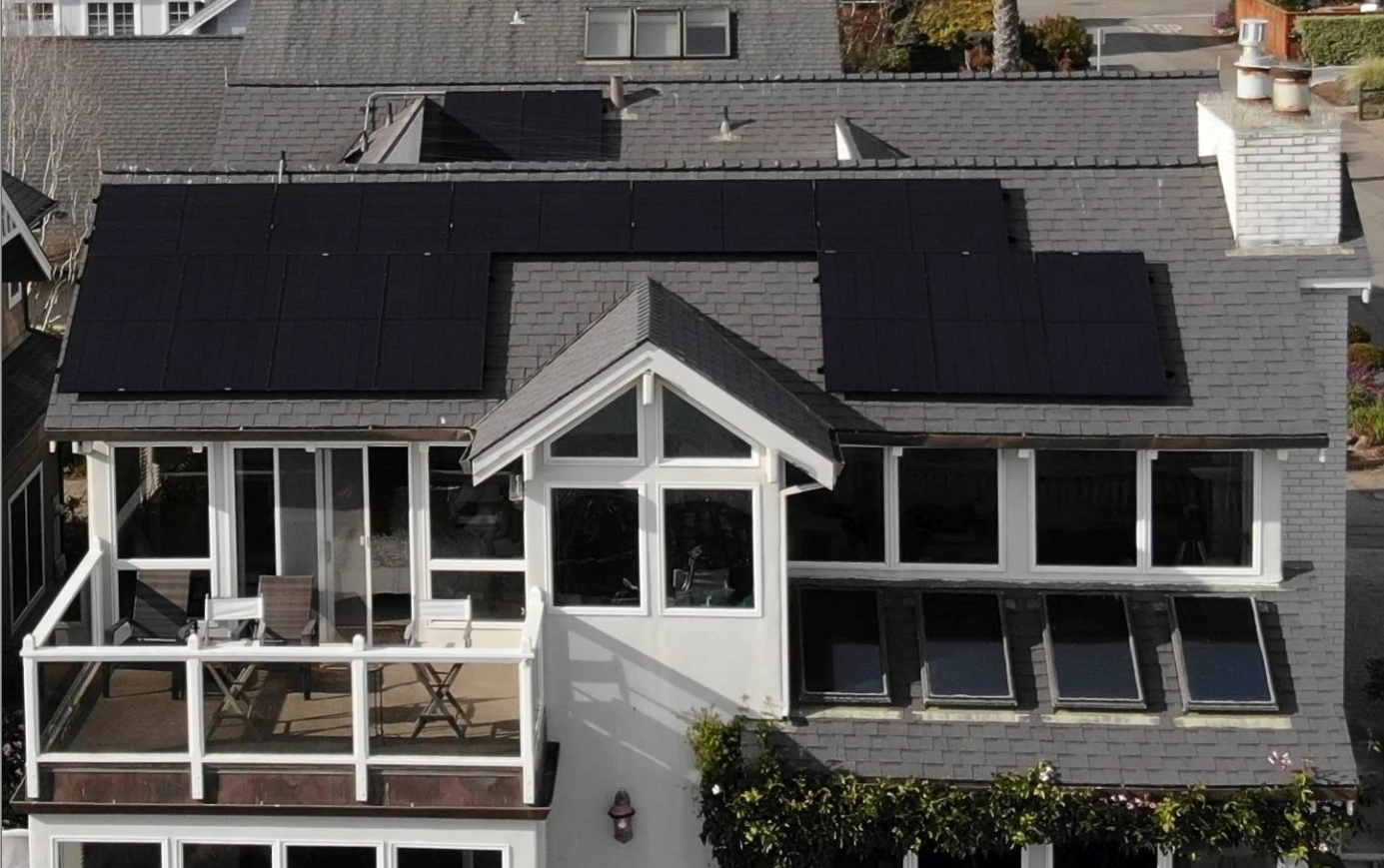 Drone shot of a home with two solar panels mounted on their rooftop